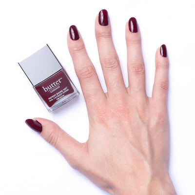 dark blackberry nail polish painted on nails and nail polish bottle