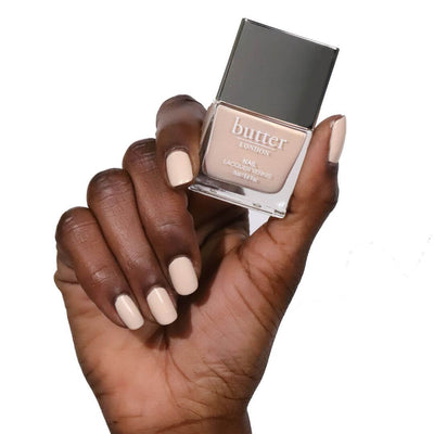 Hand holding High Street Crème Patent Shine 10X Nail Lacquer (Neutral Champagne crème with hints of gold) 
